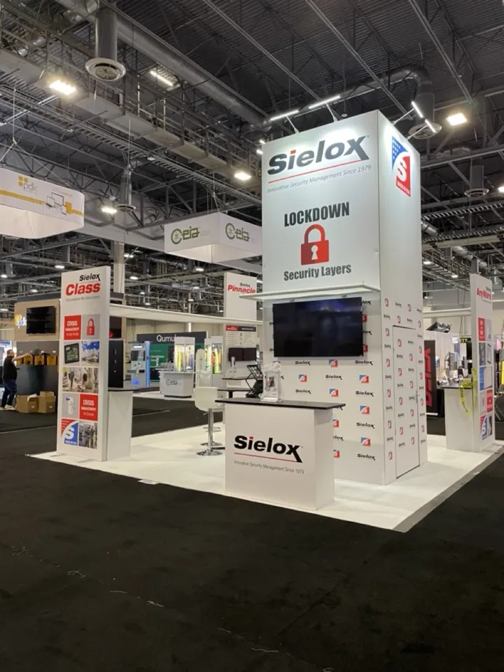 The Sielox exhibit on a show floor: a tall backlit tower and a counter, under hall lighting.